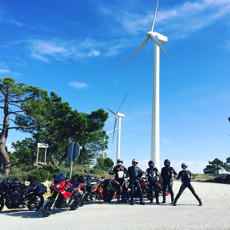 Spyder Motorcycles Tour Group for the Season Finale in Spain, a group of bikes and riders posed under wind turbines.